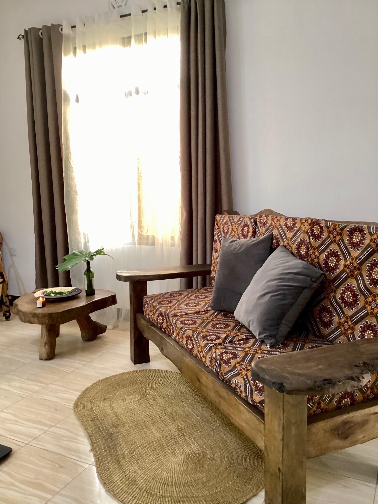 The sitting room inside an AIM Lodge cottage with a wooden sofa and woven rug