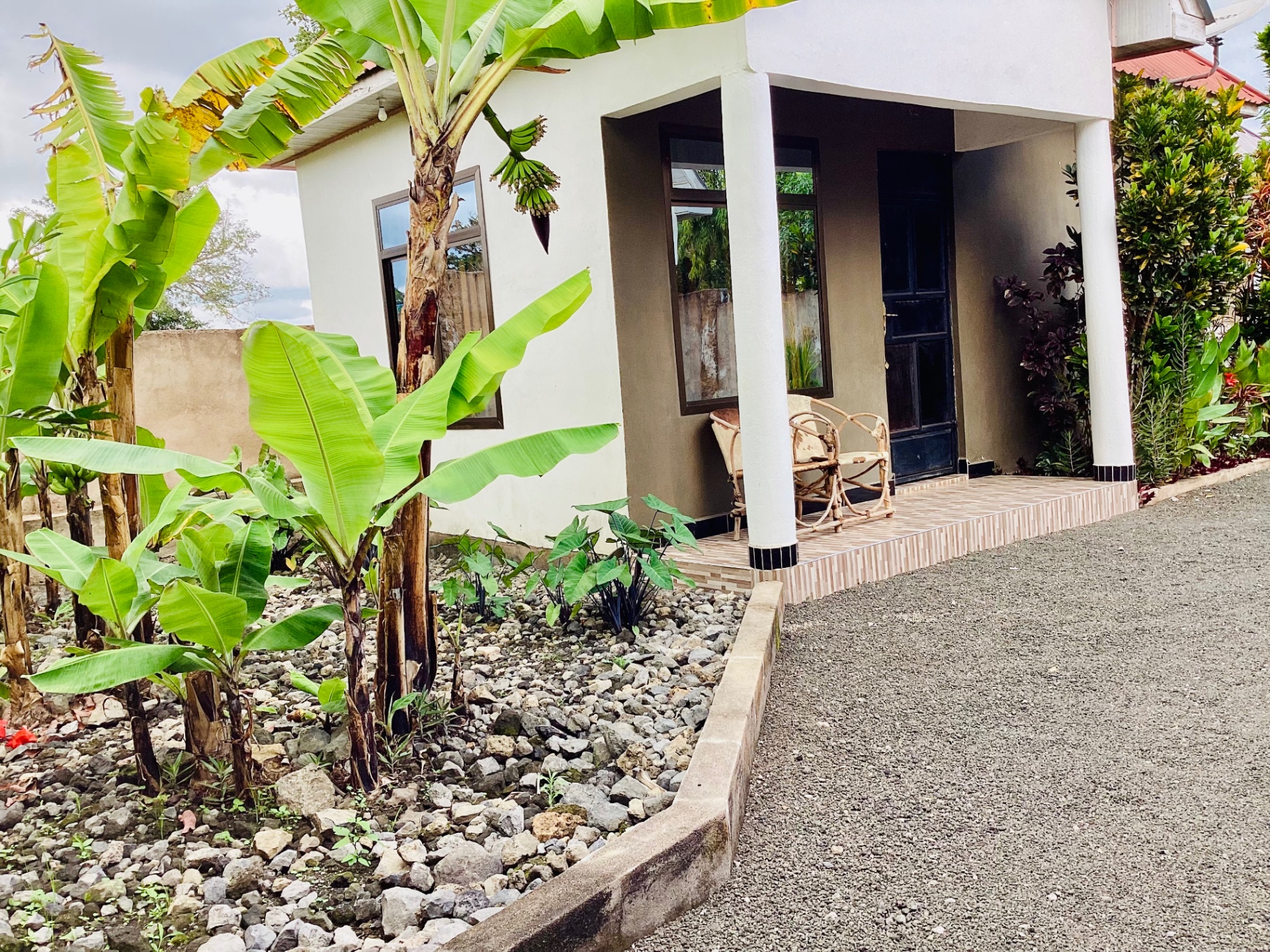 An AIM Lodge cottage with a porch, banana plants and garden